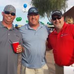 Three guys standing one holding a drink